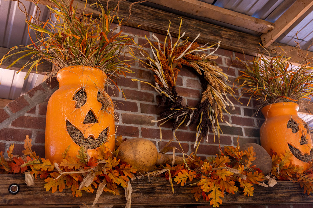 Halloween wreath on a brick wall beside lantern pumpkins